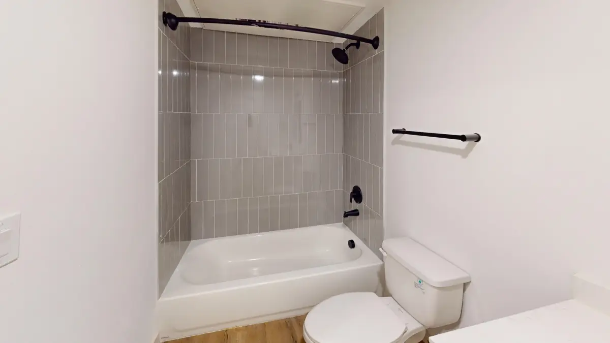 Bathroom with a gray vertical-tile tub-and-shower and black fixtures