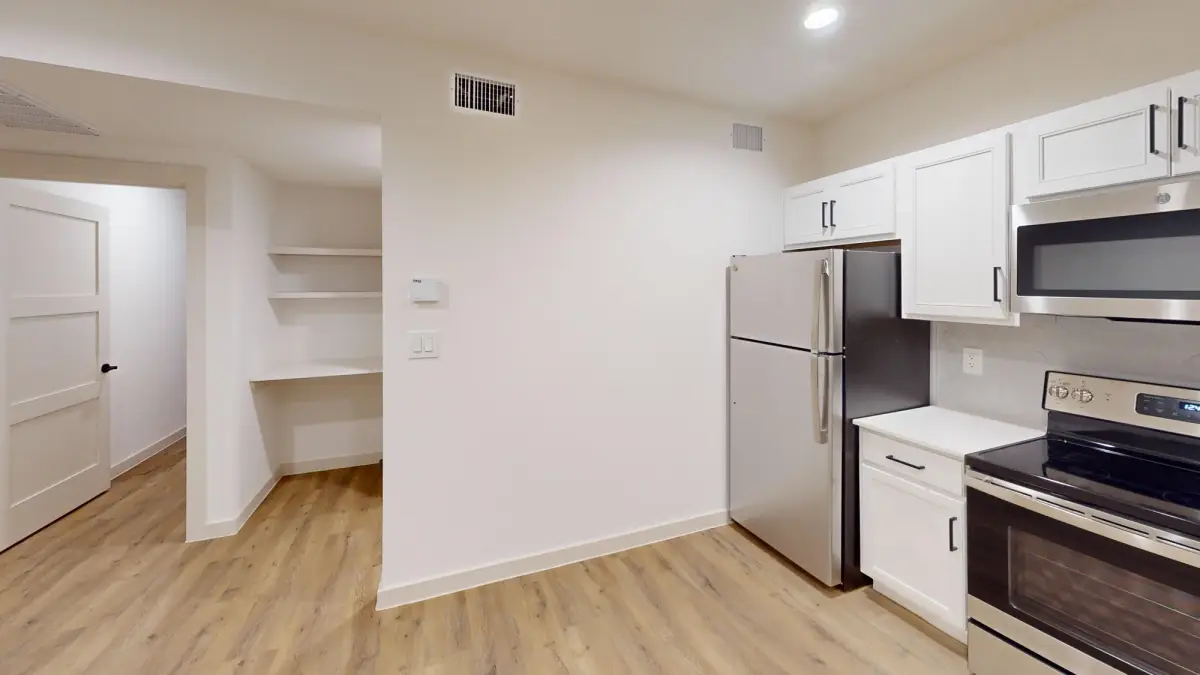 Kitchen with white cabinets and stainless appliances beside a built-in desk nook