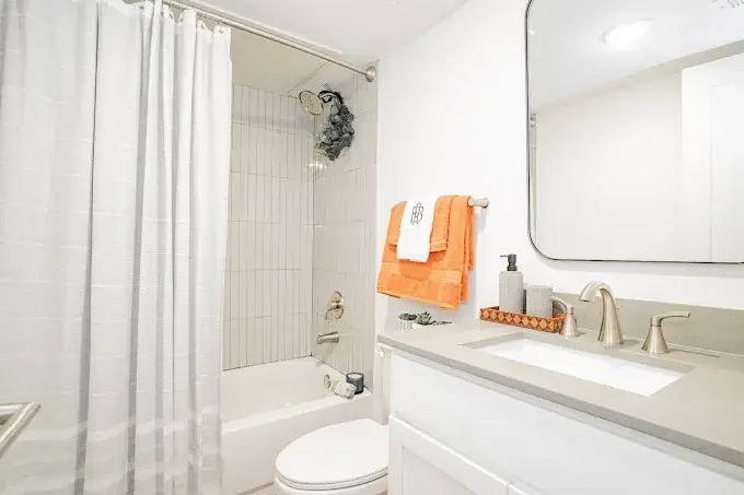 Bathroom with a white vanity, solid surface top, a white vertical-tile tub-and-shower, and brushed-nickel fixtures