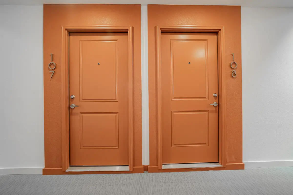 Interior corridor with two apartment doors recessed in orange-painted alcoves