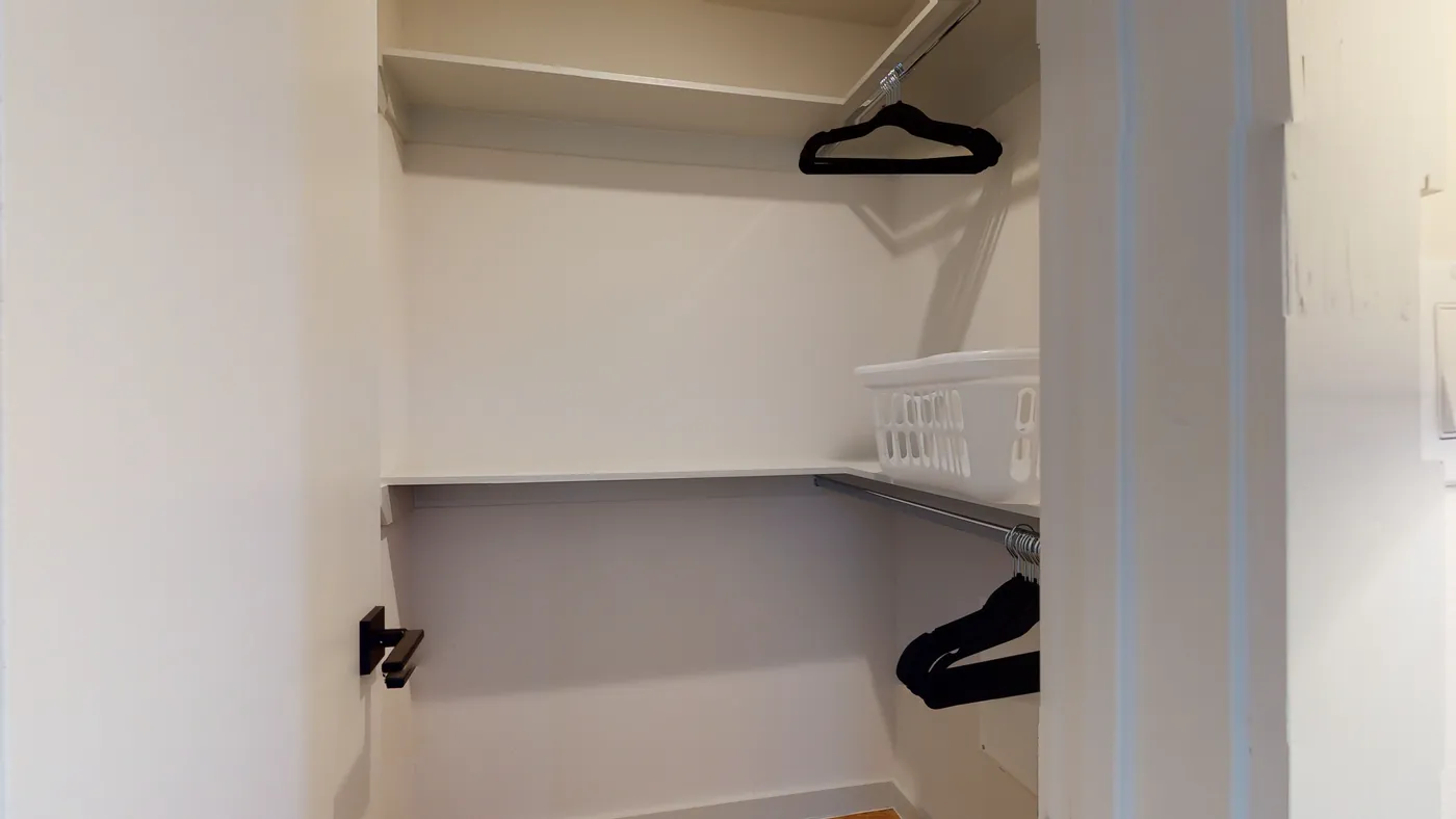 Walk-in closet with white built-in shelving, double chrome hanging rods, and velvet hangers ready for move-in