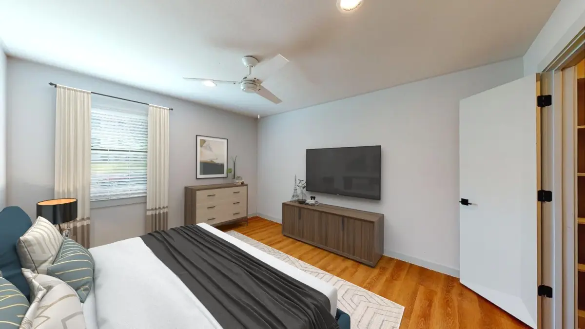 Bedroom with a bed, dresser, wall-mounted TV, and a curtained window