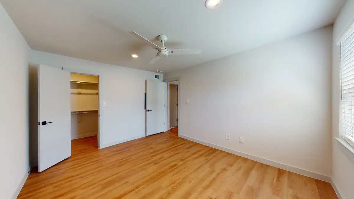 Empty bedroom with a ceiling fan, wood-look flooring, and an open walk-in closet
