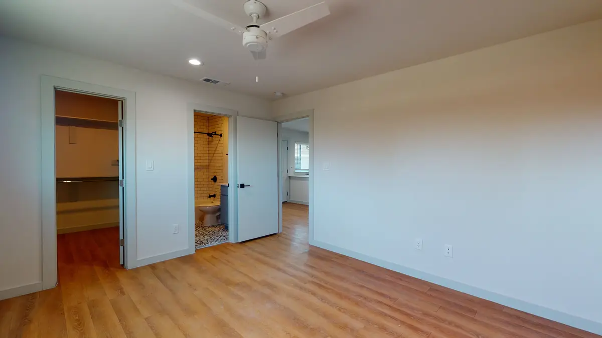 Bedroom with a ceiling fan and doorways to a walk-in closet and an ensuite bathroom
