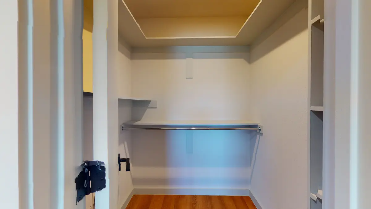 Walk-in closet with white shelving and a hanging rod