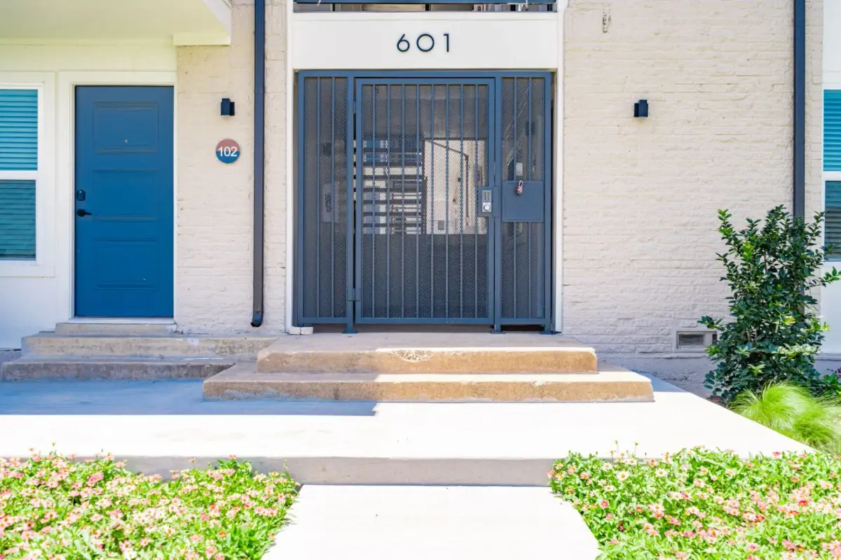 Building entry with a gated metal security door numbered 601 and a blue apartment door beside it