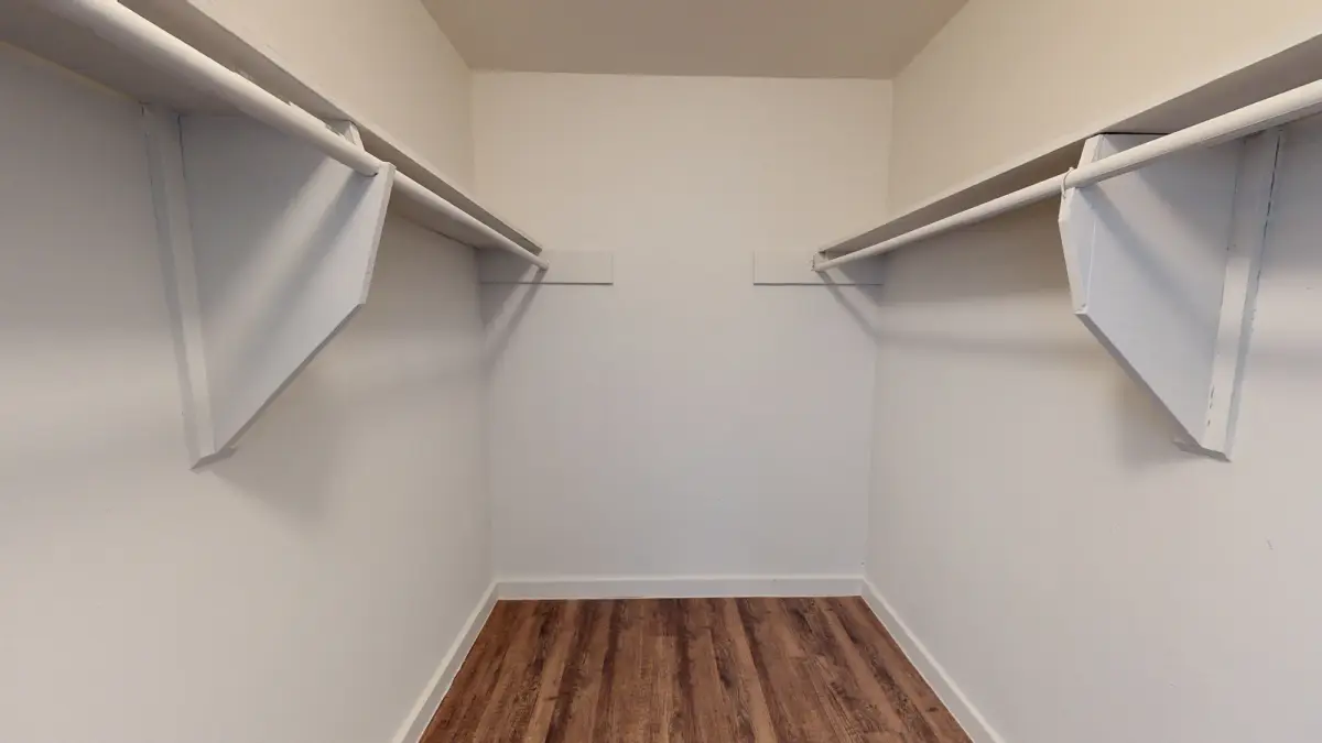 Walk-in closet with white shelving on both walls and wood-look flooring