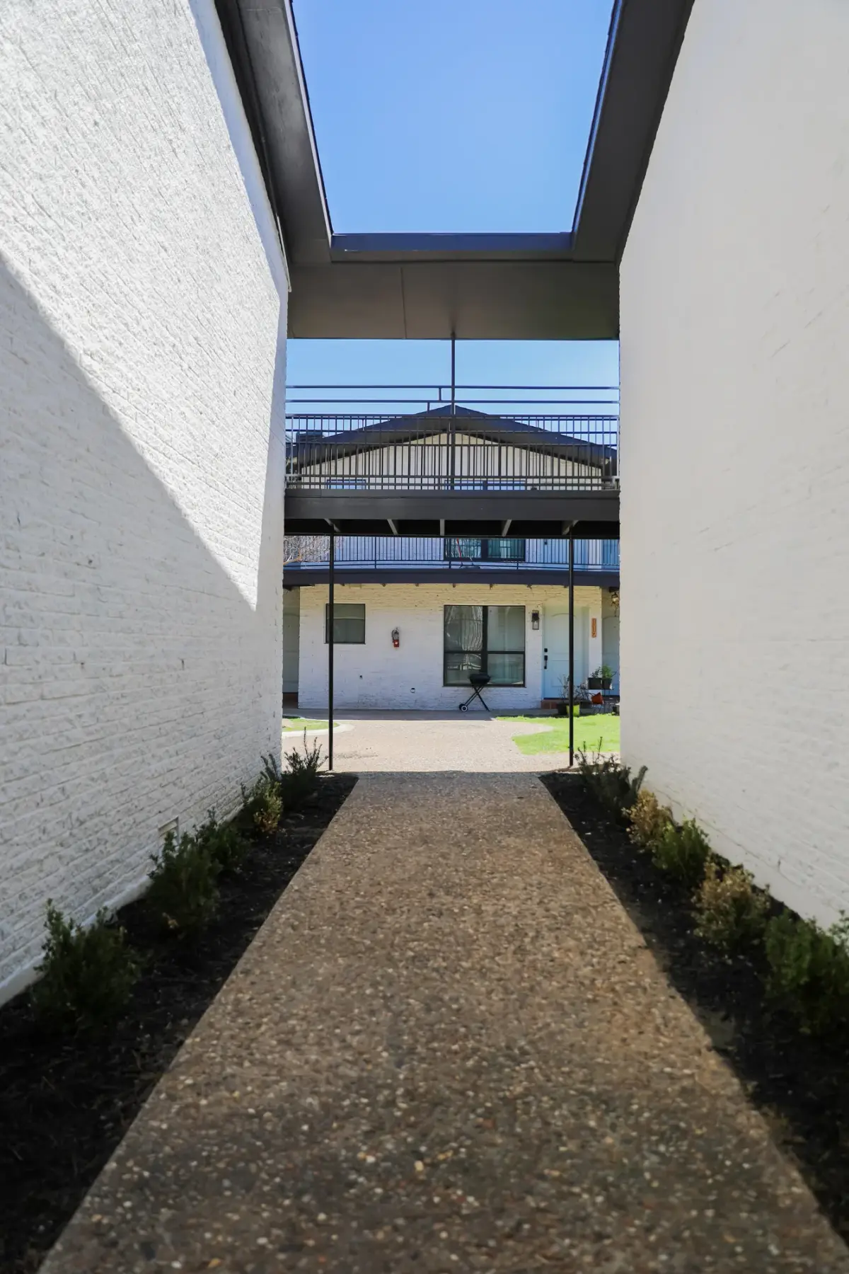 Covered breezeway passage with white-painted brick walls opening to the courtyard