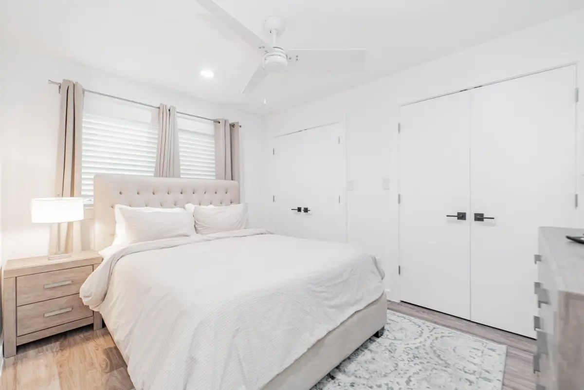 Bedroom with an upholstered bed, a dresser, double closet doors, and a ceiling fan