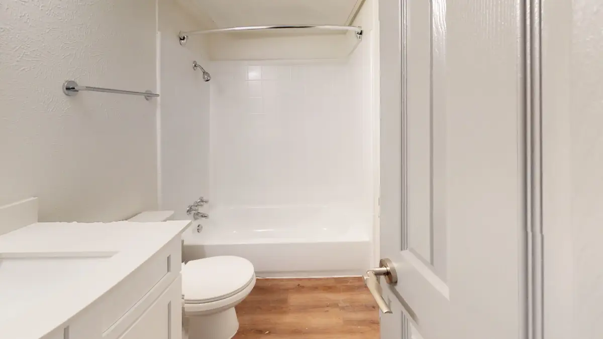 Bathroom with a white vanity, chrome fixtures, and a white tub-and-shower surround