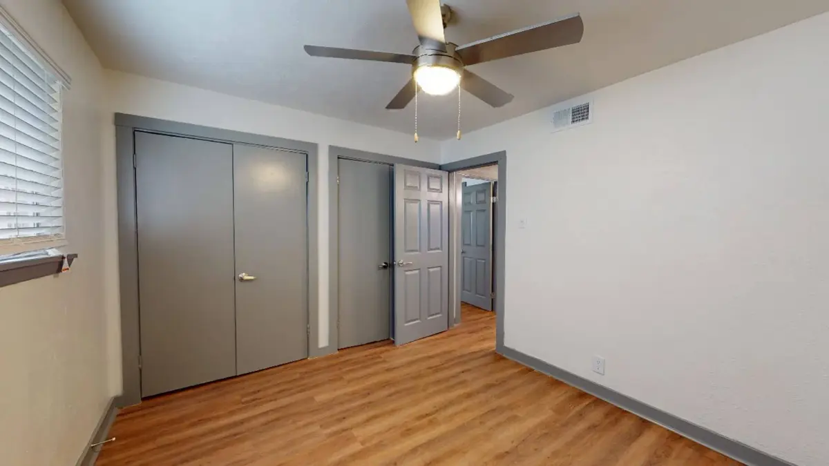 Bedroom with gray closet and passage doors, a ceiling fan, and wood-look flooring