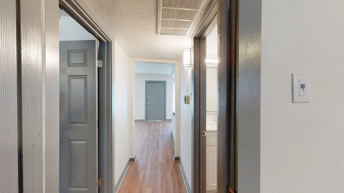 Interior unit hallway opening to the living area and a bathroom with a white vanity