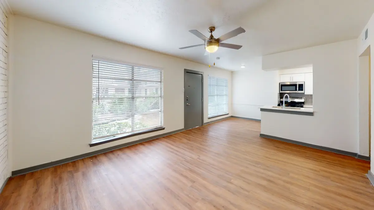 Living room with a ceiling fan, a large blinded window, and wood-look flooring