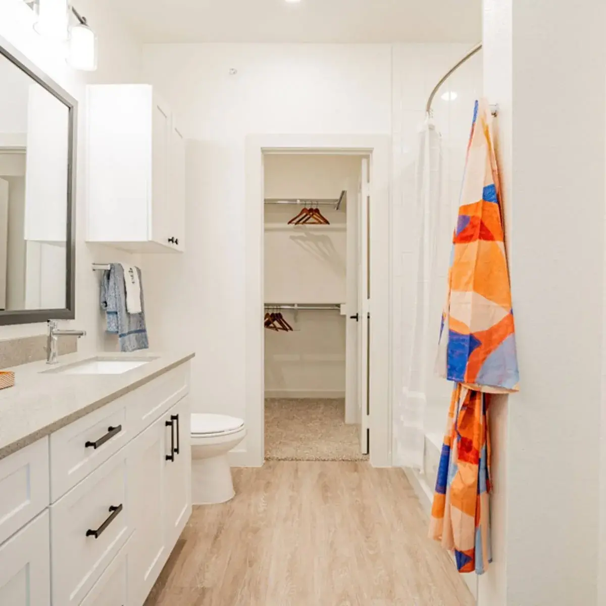Bathroom with a quartz vanity, matte black pulls and a curved-rod tub shower, opening to the walk-in closet