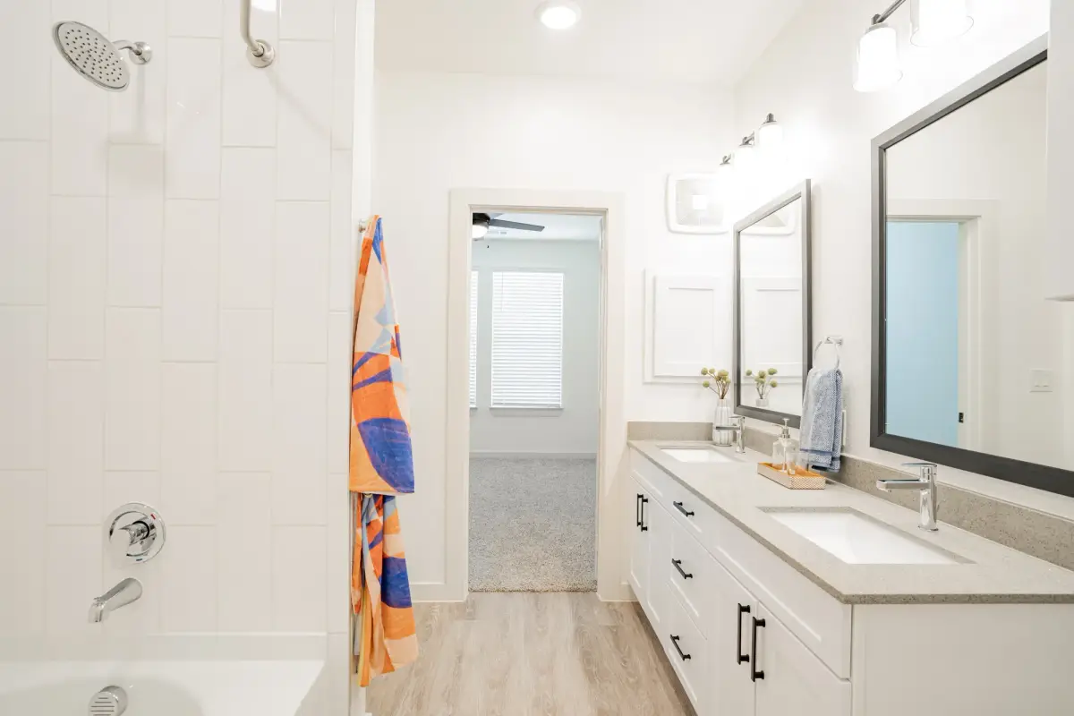 Bathroom with a double quartz vanity, framed mirrors and a tiled shower-tub
