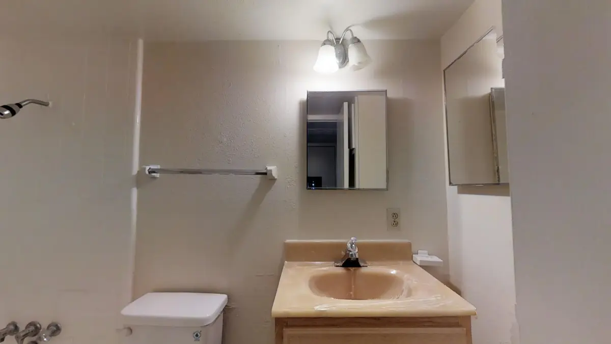 Bathroom with an oak vanity, cultured-marble sink, and a mirrored medicine cabinet