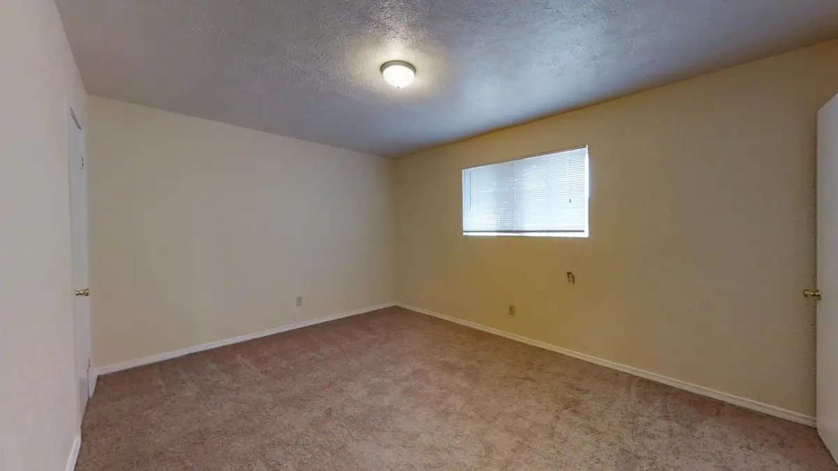 Carpeted bedroom with warm-toned walls and a window with blinds