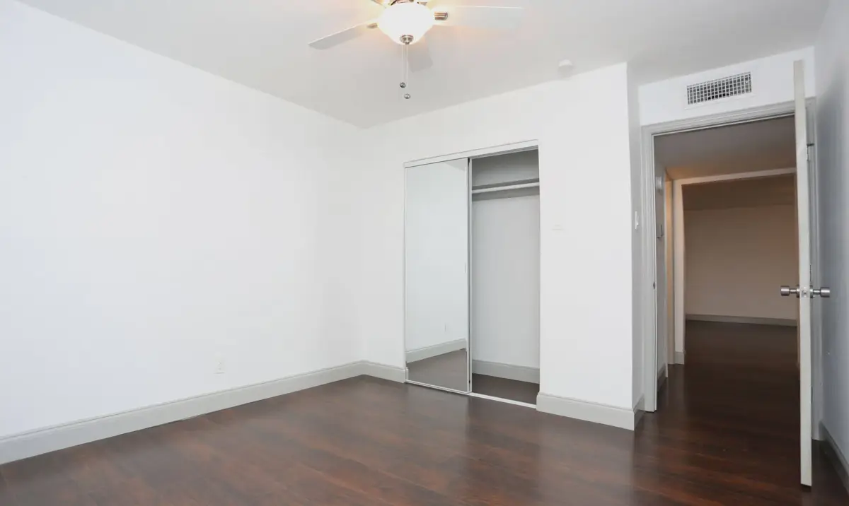 Bedroom with wood-look flooring and mirrored sliding closet doors