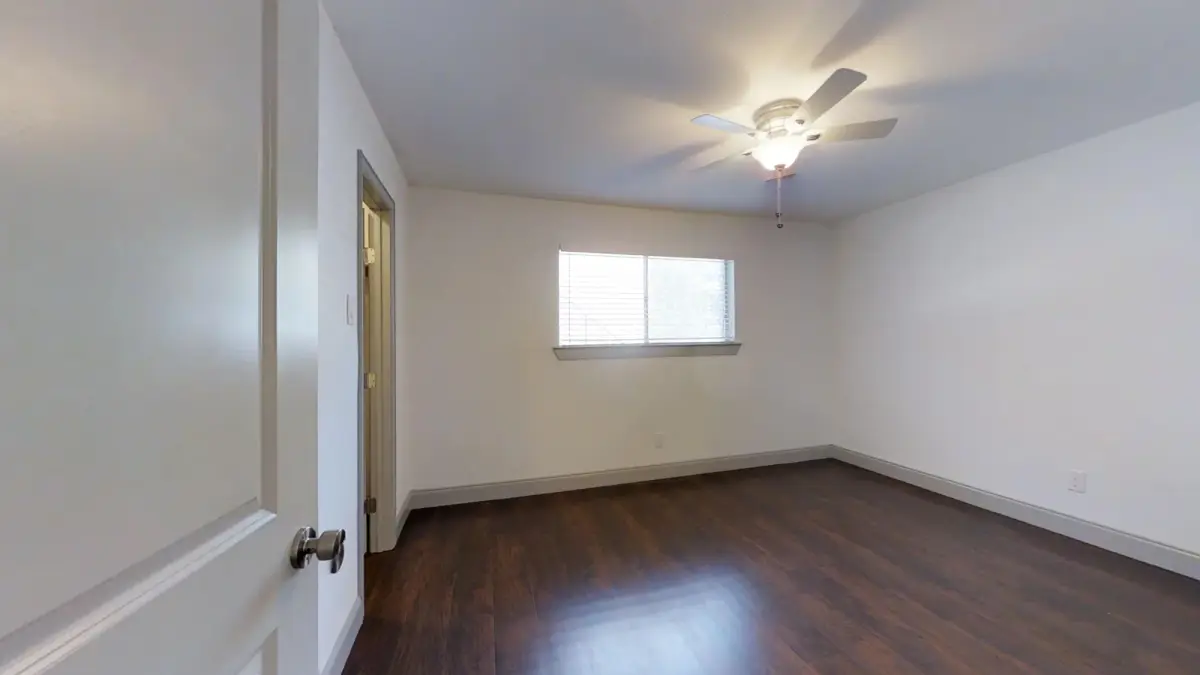 Bedroom with wood-look flooring, a ceiling fan, and a window with blinds