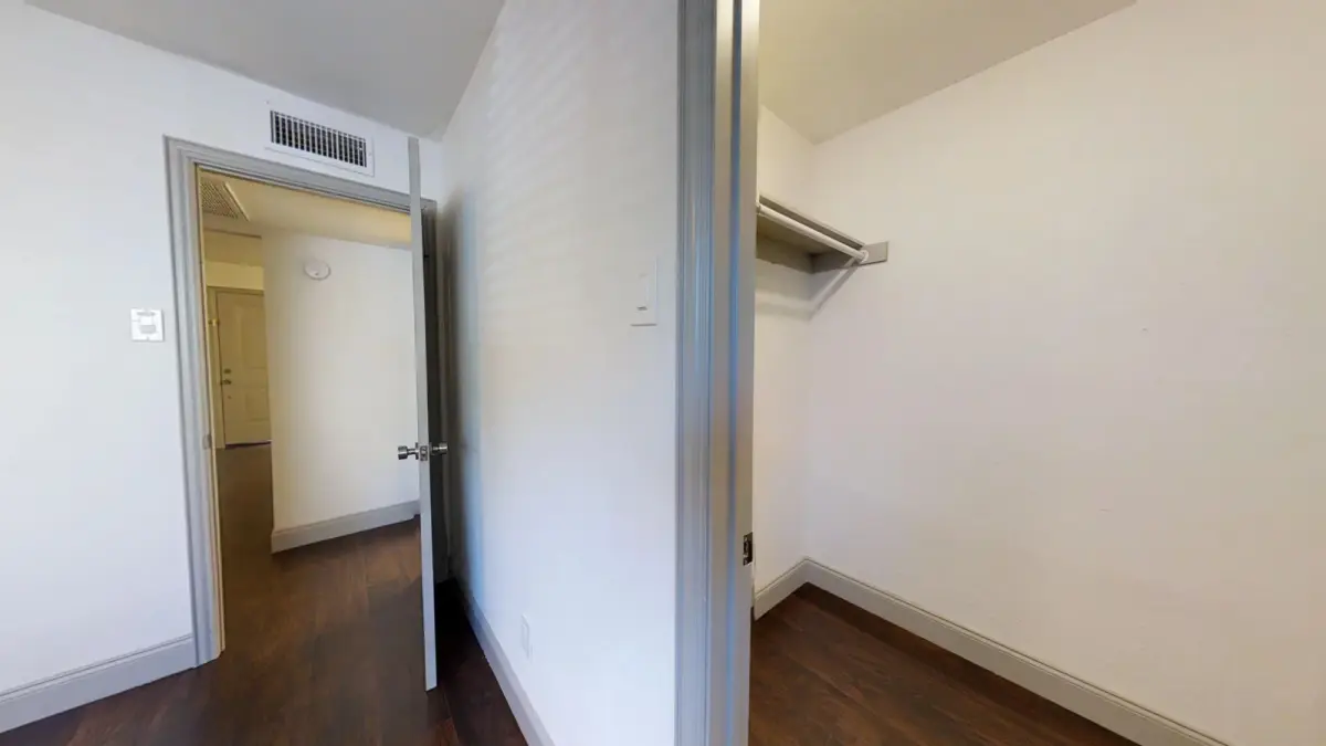 Reach-in closet with a shelf and rod beside the bedroom hallway
