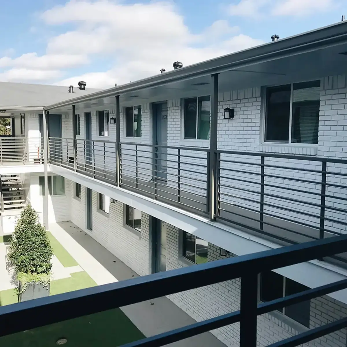 View along an upper exterior walkway with metal railings overlooking the courtyard