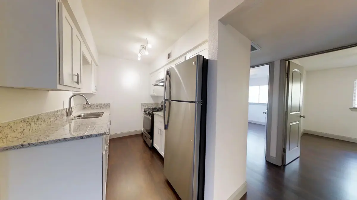 Galley kitchen with stainless-steel appliances opening to an adjoining room through double doors