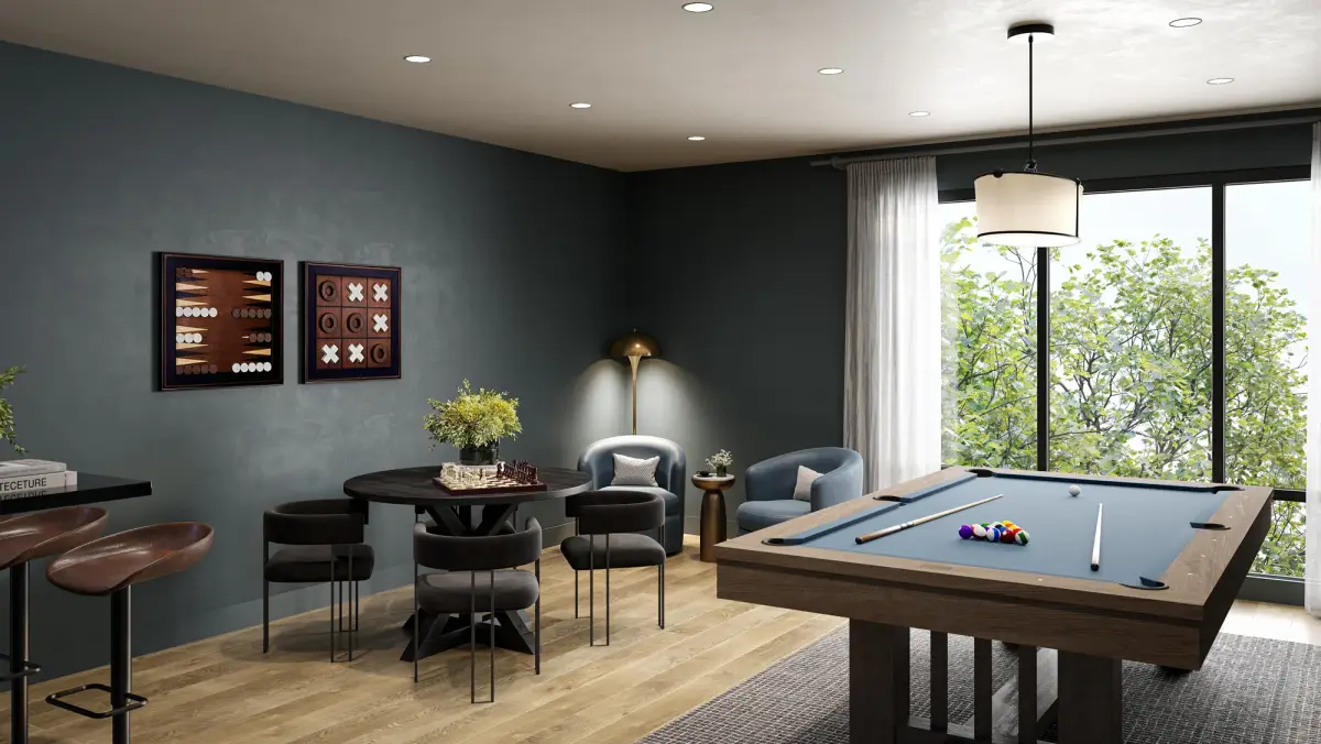Game lounge with blue-felt pool table, round chess table, gray chairs, and backgammon wall art by a bright window