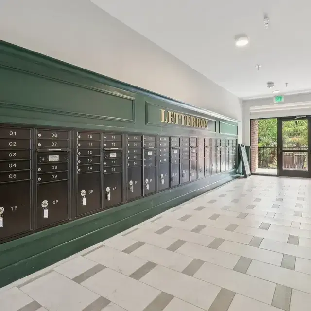 Mail room with rows of bronze letterboxes set in green millwork under gold LETTERBOX lettering, on checkered tile