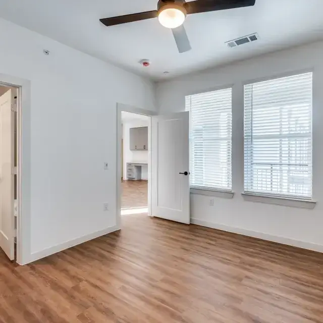 Bedroom with two blinded windows and a doorway to a built-in desk nook