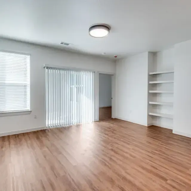 Room with a sliding glass patio door behind vertical blinds and built-in floating shelves