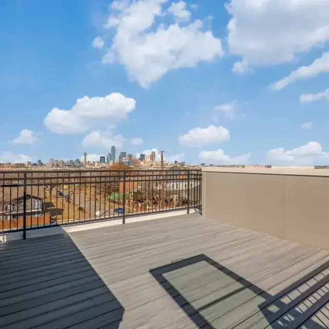 Rooftop deck with metal railings and a distant view of downtown Dallas