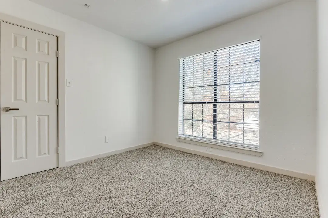 Empty carpeted bedroom with a ceiling fan and an open walk-in closet