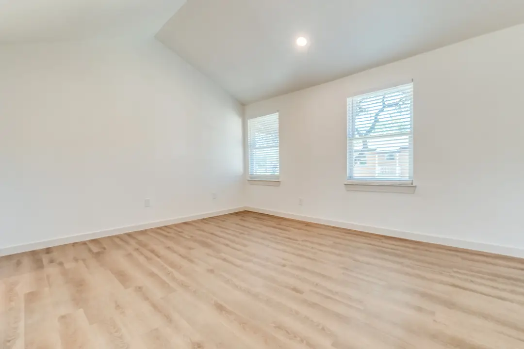 Empty bedroom with a vaulted ceiling and two blinded windows
