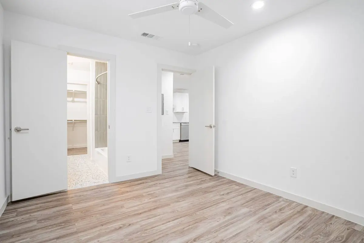 Bedroom with a ceiling fan and doorways to a tiled bathroom and a walk-in closet