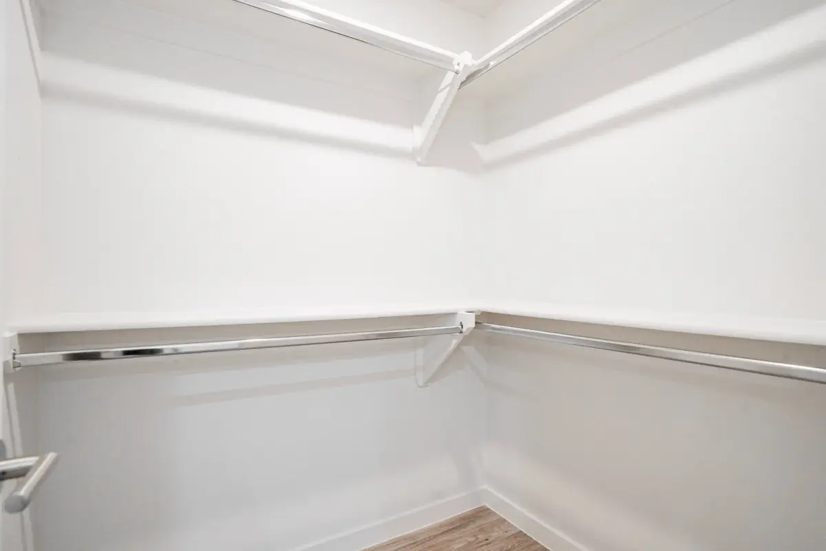 Walk-in closet with white shelving and chrome hanging rods