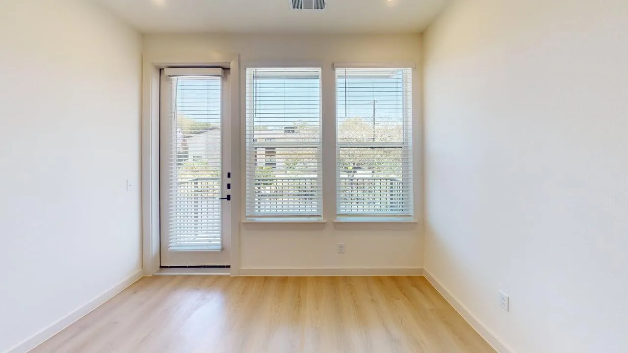 Living room of a finished A1 one bedroom at The Parker, with oak-style floors and a glass balcony door