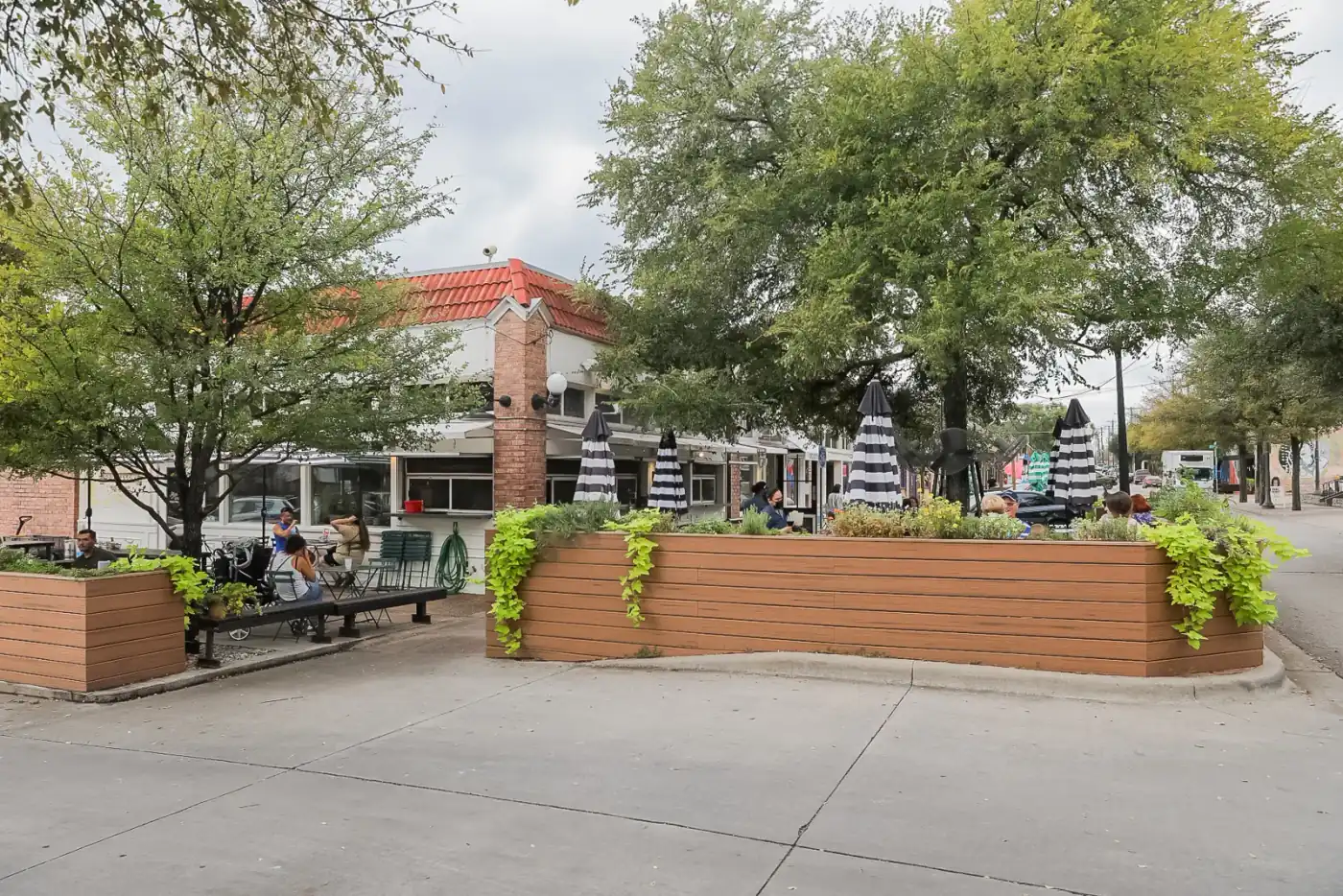 A tree-lined Bishop Arts District street in Oak Cliff with sidewalk dining patios