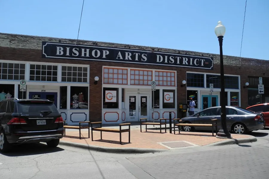 The Bishop Arts District sign above shops and sidewalk patios in Oak Cliff