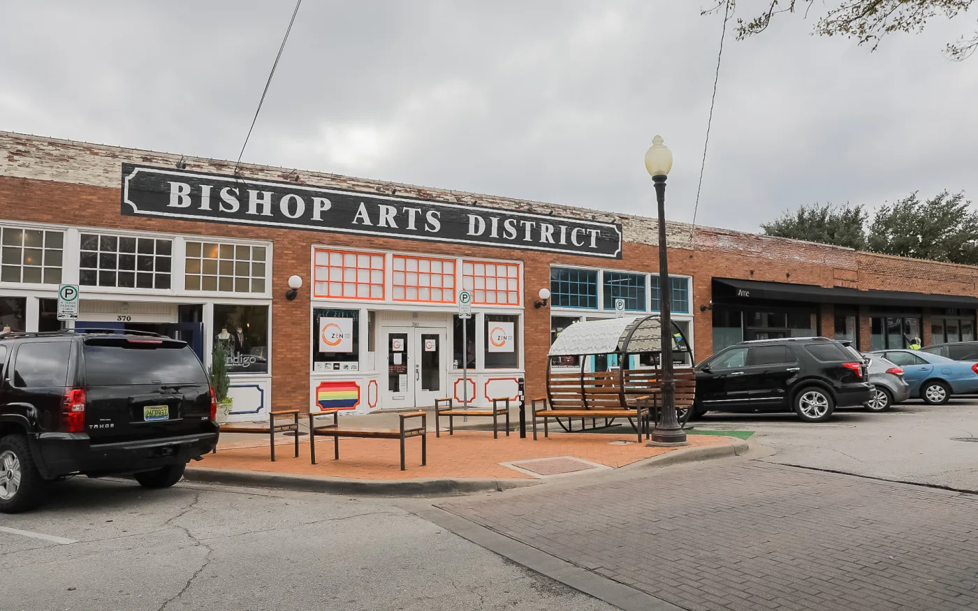 The painted Bishop Arts District sign over the brick storefront row