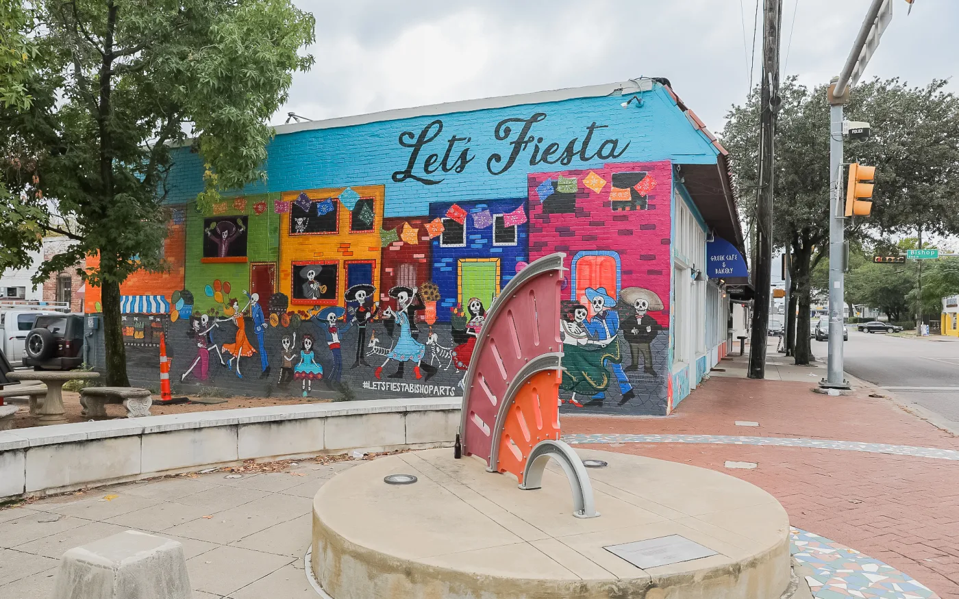 The Let's Fiesta mural and the sundial sculpture at a corner plaza off Bishop Avenue